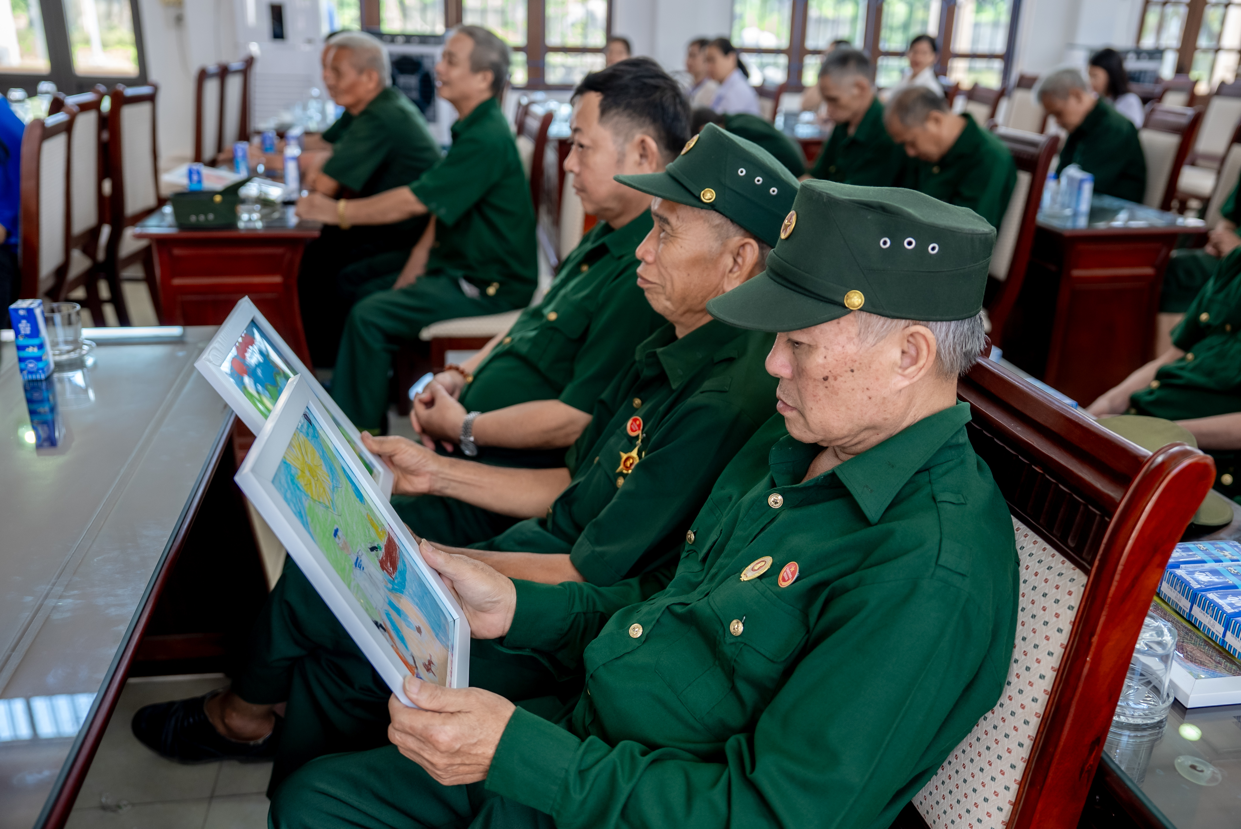 C&aacute;c b&aacute;c cựu chiến binh chăm ch&uacute; đọc những d&ograve;ng chữ nhỏ, được c&aacute;c em gửi k&egrave;m trong mỗi bức tranh (Ảnh: Duy Cường). &nbsp;