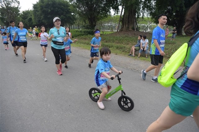 Một em nhỏ mang theo chiếc xe đạp y&ecirc;u th&iacute;ch v&agrave;o đường đua để bắt kịp tốc độ của phụ huynh v&agrave; c&aacute;c bạn.